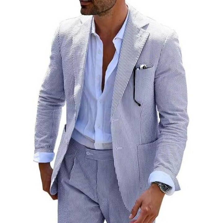Ein Mann in einem modernen gestreiften Zweireiher mit Revers, der in einer eleganten Hochzeitslocation posiert.