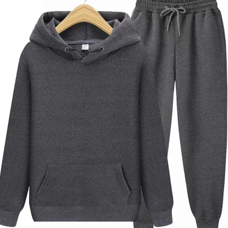 Mann, der einen lässigen zweiteiligen Kapuzenpullover und eine Jogginghose in einer neutralen Farbe trägt, in einer entspannten Umgebung.