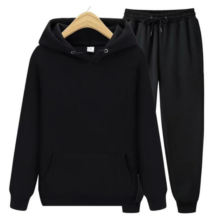 Mann, der einen lässigen zweiteiligen Kapuzenpullover und eine Jogginghose in einer neutralen Farbe trägt, in einer entspannten Umgebung.