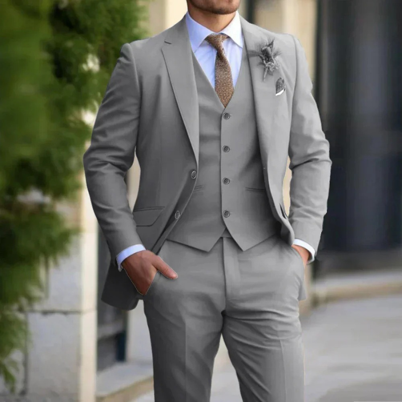 Mann in einem klassischen dreiteiligen Anzug steht selbstbewusst bei einer Hochzeit im Freien
