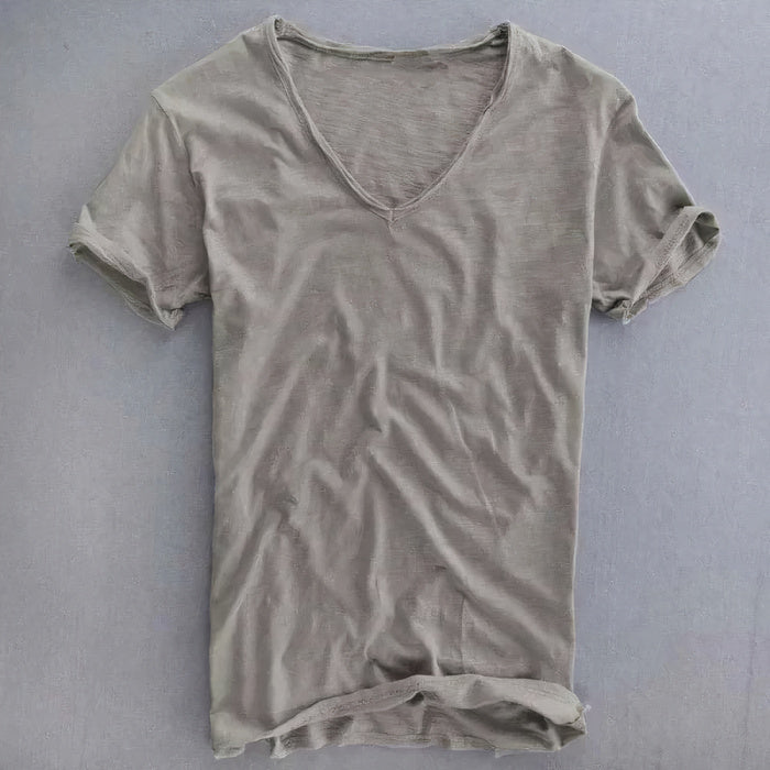 Mann trägt ein lässiges Sommer-T-Shirt mit V-Ausschnitt und Jeans in einer lässigen Umgebung im Freien
