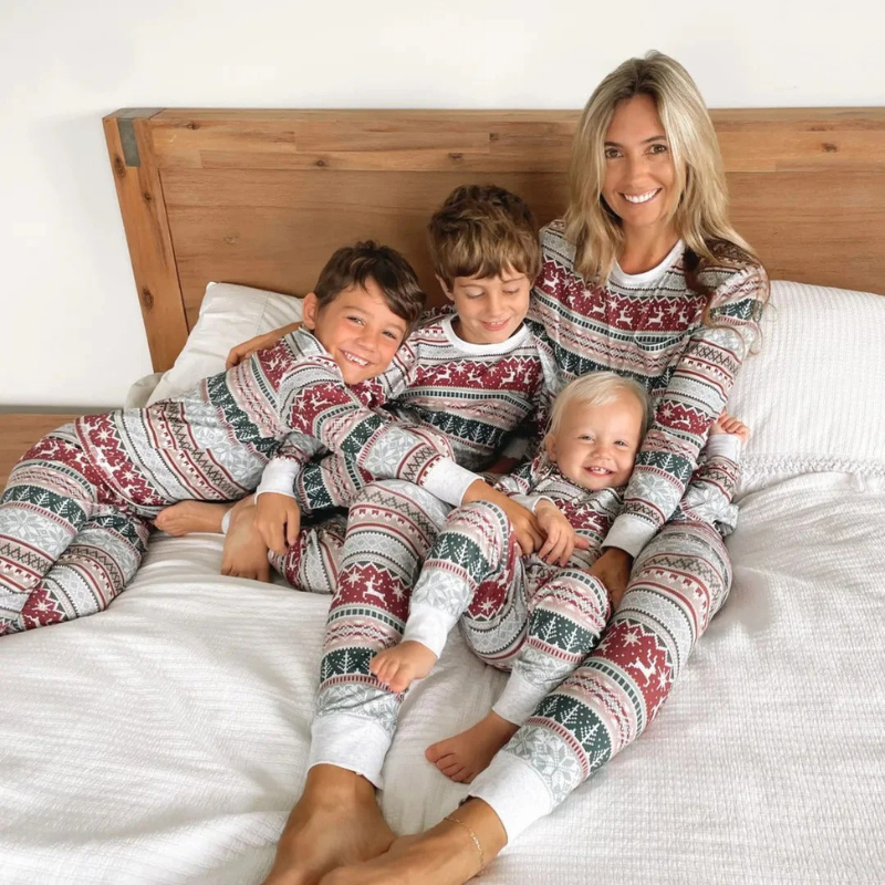 Lächelnde Familie in passenden Weihnachtspyjamas, versammelt in einem gemütlichen Wohnzimmer.