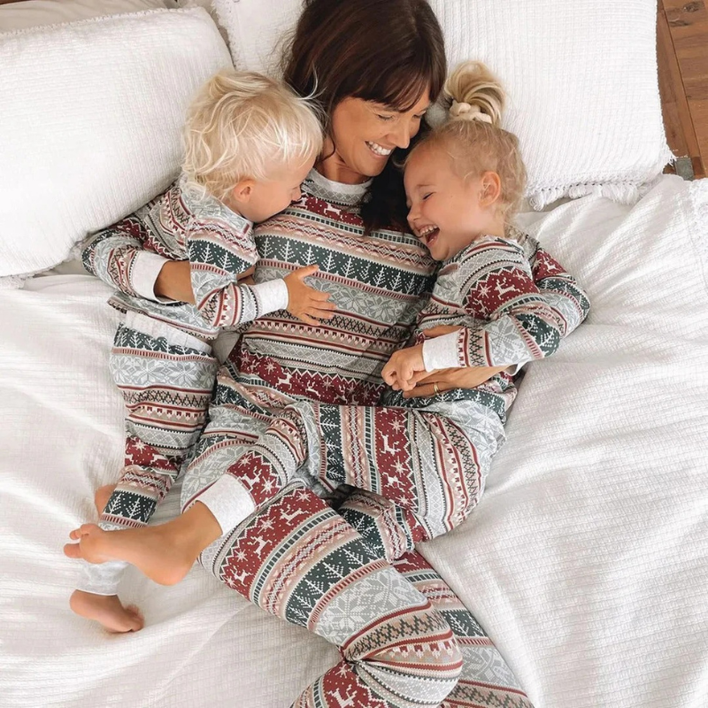 Lächelnde Familie in passenden Weihnachtspyjamas, versammelt in einem gemütlichen Wohnzimmer.